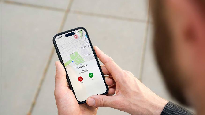  En mand kigger på sin telefon, hvor han har fået en hjerteløber-alarm i hjerteløber-appen