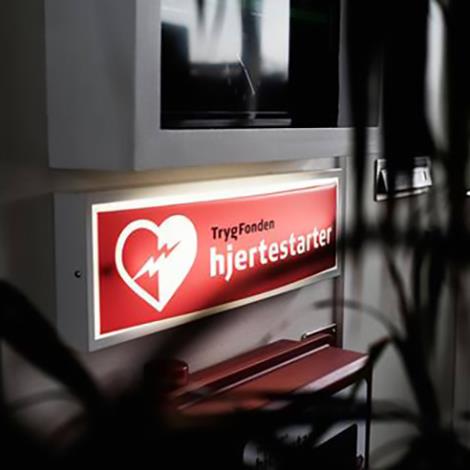 Et lysende skilt hvor der står TrygFonden hjertestarter